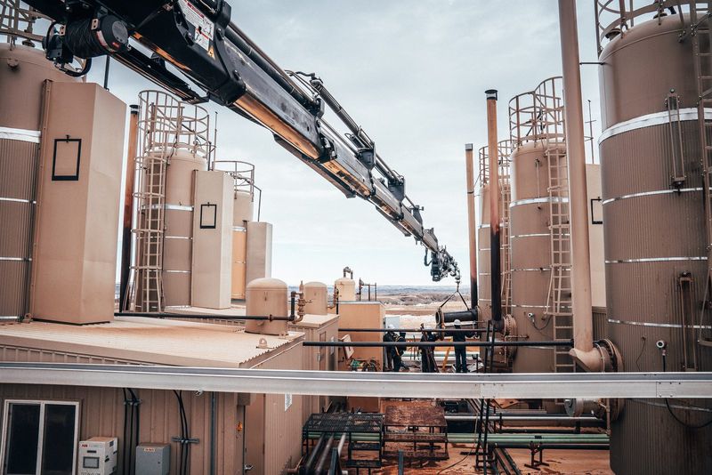 Crane boom reaching in between tanks on a battery