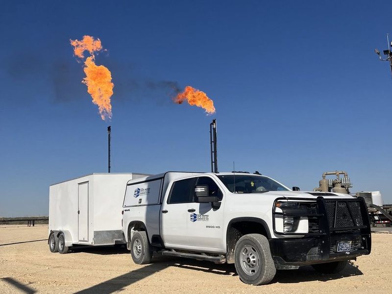 Elite service truck on location with flares burning at dusk